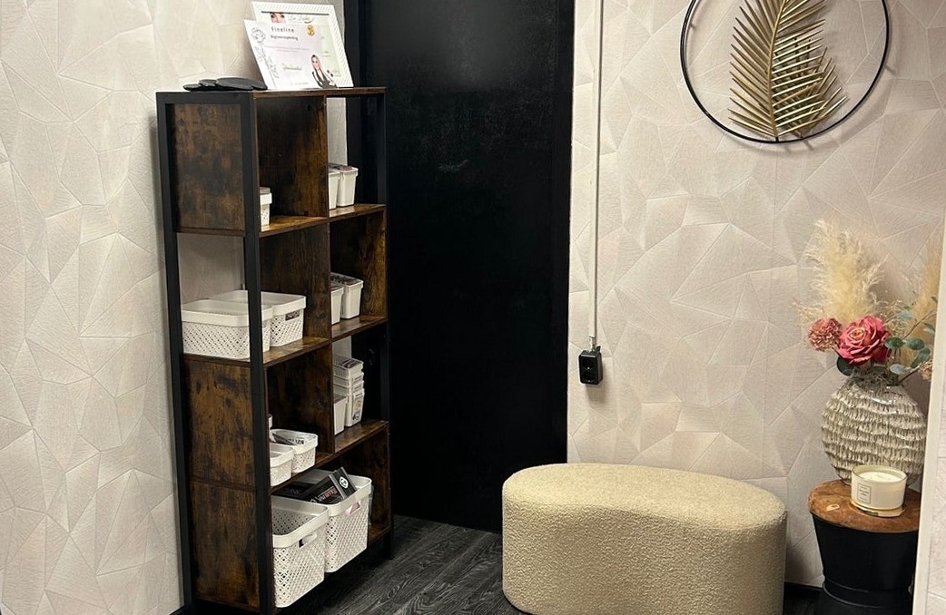 Een hoek van de salon met een open kast en een poef