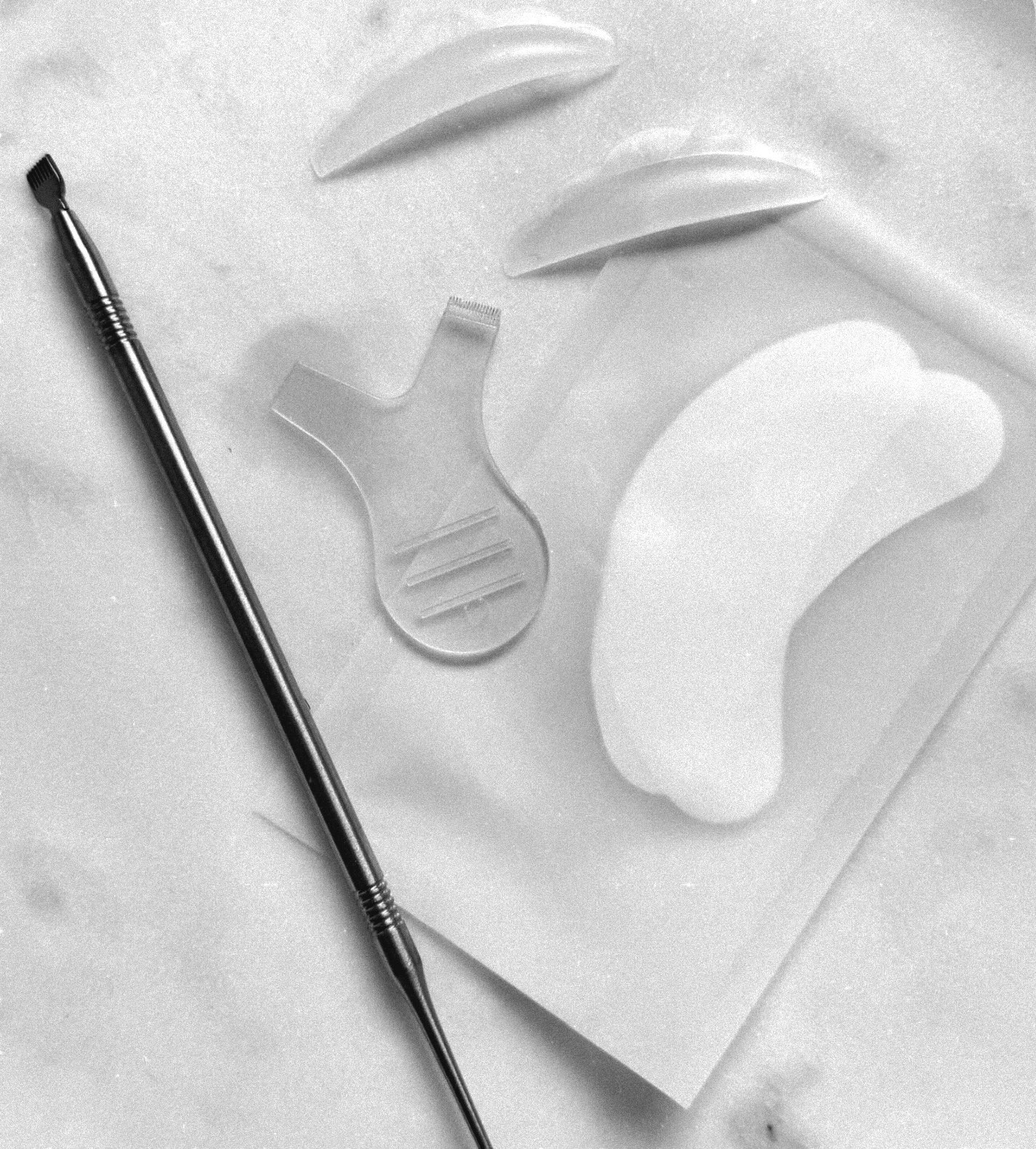 Lash lift pads en een lash lift tool op marmer, zwart-wit